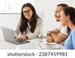 Small photo of Satisfied young husband and wife in dialogue with a mature real estate advisor, deliberating over paperwork in an office environment, looking at laptop screen