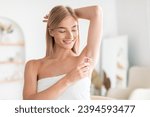 Small photo of Armpit Hair Removal. Young Blonde Lady Shaving Armpits Using Safety Razor, Removing Hair In Bathroom At Home. Woman Making Underarms Depilation Raising Arm Standing Wrapped In Towel