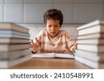 Small photo of Puzzled black boy making homework surrounded by towering piles of books, stressed preteen male kid suffering confusion and puzzlement while looking in open workbook, having difficult task