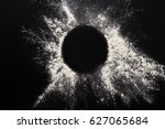 Abstract background. Sprinkled wheat flour circle, round spot on black. Top view on blackboard. Baking concept, cooking dough or pastry.