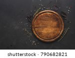 Round wooden plate with herbs and salt on dark wooden background top view