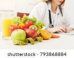 Nutritionist desk with healthy fruit, juice and measuring tape. Dietitian working on diet plan. Weight loss and right nutrition concept