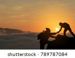 Two friends helping each other and with teamwork trying to reach the top of the mountains during wonderful summer sunset.