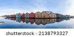 Wide panoramic view of old colorful wooden houses with reflections in river Nidelva in the Brygge district in Trondheim, Norway