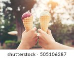 Woman's hands holding melting ice cream waffle cone in hands on summer light nature background
