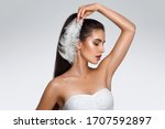 Small photo of Portrait of attractive Caucasian woman with raised hand. beautiful young girl holds feather in hands and looks at armpit. Smooth clean skin of the face and body. concept care, epilation armpit