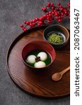 Small photo of Close up of matcha big tangyuan (tang yuan) with sweet matcha soup in a bowl on wooden table background for festival food.
