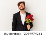 Young arab man holding bouquet of roses isolated on white background dreaming of achieving goals and purposes