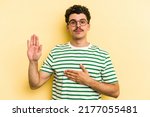 Small photo of Young caucasian man isolated on yellow background taking an oath, putting hand on chest.