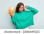 Small photo of Young caucasian woman holding potato crips isolated on blue background feels proud and self confident, example to follow.