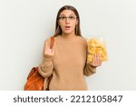 Small photo of Young student Indian woman holding crips isolated on white background pointing upside with opened mouth.