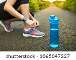 Staying hydrated and drinking water concept. Woman getting ready for run with bottle of water next to her. Focus on bottle of water. 