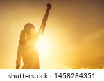 Woman power, victory and winning concept. Woman with fist in the air at sunset. 