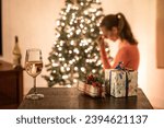 Sad tired woman with hand over face sitting next to Christmas tree 