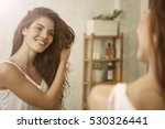 Girl touching her hair and smiling while looking in the mirror 