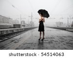 Woman with umbrella standing on the platform of a train station