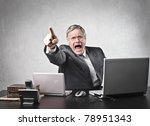 Angry senior businessman sitting at his desk and screaming
