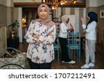 Portrait of one Muslim woman with hijab at home - Two arab millennials talking in an apartment and a friend is posing in the foreground