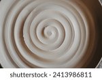 Small photo of A beautiful spiral, a helical line on a clay surface. Pottery, clay texture decorated with a spiral notch. Abstract clay background Macro, top view
