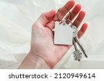 Small photo of Keychain house shaped mockup in hand. Blank white sublimation keychain. Copy space.