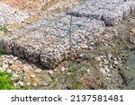 Small photo of Stone walls, protection from backshore erosion. Stones in a metal mesh. Gabion wall constructed using steel wire mesh basket. Steel gabion filled with granite rocks at river bank.