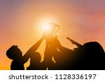 Silhouette of Business team with clipping path holding award trophy show their victory when business success sunset background