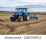 Small photo of Prestwick, South Ayrshire, Scotland - October 27th 2023: New Holland tractor and plough at the 59th Scottish Ploughing Championships ready for ploughing