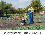 Small photo of Man cultivates the ground in the garden with a tiller, preparing the soil for sowing.