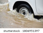 The front wheel of the pickup car was passing the urban road which fulled of floodwater during the heavy raining day. (Selective focus)