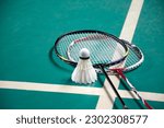 Badminton sport equipments, rackets and shuttlecocks on dark floor of indoor badminton court, soft focus, concept for badminton playing lovers around the world, copy space.