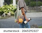Small photo of Woman walking and carrying white mesh string knitted shopping bag with groceries and reuseble metal cup. Eco friendly, reusable shopping bag. Zero waste and plastic free concept.