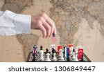 Small photo of Politician's hand moves a chess piece with a flag. Conceptual photo of a political game. retaliatory move USA