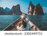 Travel summer vacation concept, Happy solo traveler asian woman with hat relax and sightseeing on Thai longtail boat in Ratchaprapha Dam at Khao Sok National Park, Surat Thani Province, Thailand
