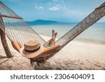 Summer travel vacation concept, Happy traveler asian woman with hat relax in hammock on beach in Koh Rap, Samui, Surat Thani, Thailand