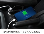 Mobile phone ,smartphone, cellphone is charged ,charge battery with usb charger in the inside of car. modern black car interior.