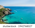 View of the rocky coast of the sea, the lagoon of the beautiful turquoise clear water and the luxury sailing boat or yacht docked on sunny day. Vacation concept