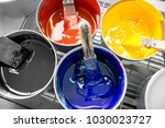 Four open buckets with CMYK paints at the printing manufacturing