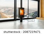 Small photo of Cozy living room with modern fireplace and panoramic window with great view on the snowy mountains. Concept of rest in houses or cabins on nature. Solitude in nature and escape from everyday life