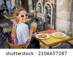 Woman eating italian pasta and drinking wine at restaurant on the street in Rome. Concept of Italian gastronomy and travel. Stylish woman with sunglasses and colorful hair shawl