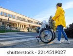 Small photo of Mother pushing wheelchair with her daughter, young girl living with cerebral palsy, on their way to therapy. Cerebral palsy is lifelong condition that affects movement and co-ordination.
