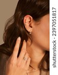 Small photo of Cropped close-up shot of a young woman with asymmetrical gold ear cuffs. Female with gold ear cuffs, side view