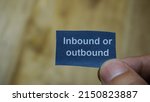 Small photo of Inbound or outbound. Man holding a paper note message with the written word "Inbound or outbound" Businessman's hand. Business, signs and symbols concept, Inbound or outbound.
