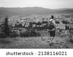 Small photo of A tourist with backpack poses against the backdrop of a densely populated area. Wretched high-rise buildings, dark gloomy tones. Top view. skyscrapers. Tbilisi Georgia. black and white