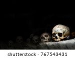 Small photo of view of an old, cracked and damaged human skull on the dark shelves of the crypt. death, appocalypstic concept, cannibalism