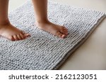 Small photo of Child foots step on a gray doormat