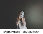 Small photo of woman covers her face with a mask to protect herself, concept of loneliness and introspection