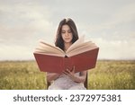 Small photo of woman reading a gigantic book sitting in the middle of nature, concept of knowledge