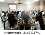 Small photo of Rear view of college students listen to teacher teaching and explaining lesson in classroom