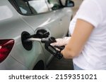 Woman is refueling at gas station. Female hand filling benzine gasoline fuel in car using a fuel nozzle. Petrol prices concept. Close-up of hand. Fuel shortage in Ukraine
