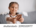 Small photo of Little crafty girl eats sweets at home. Kid eating chocolate and have fun. Chaos at home. Focus on hands